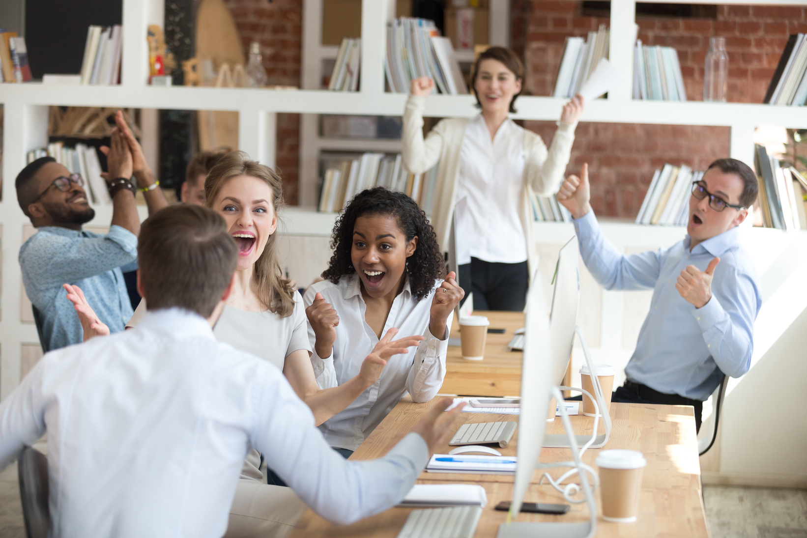 Male employee share good news with excited diverse colleagues